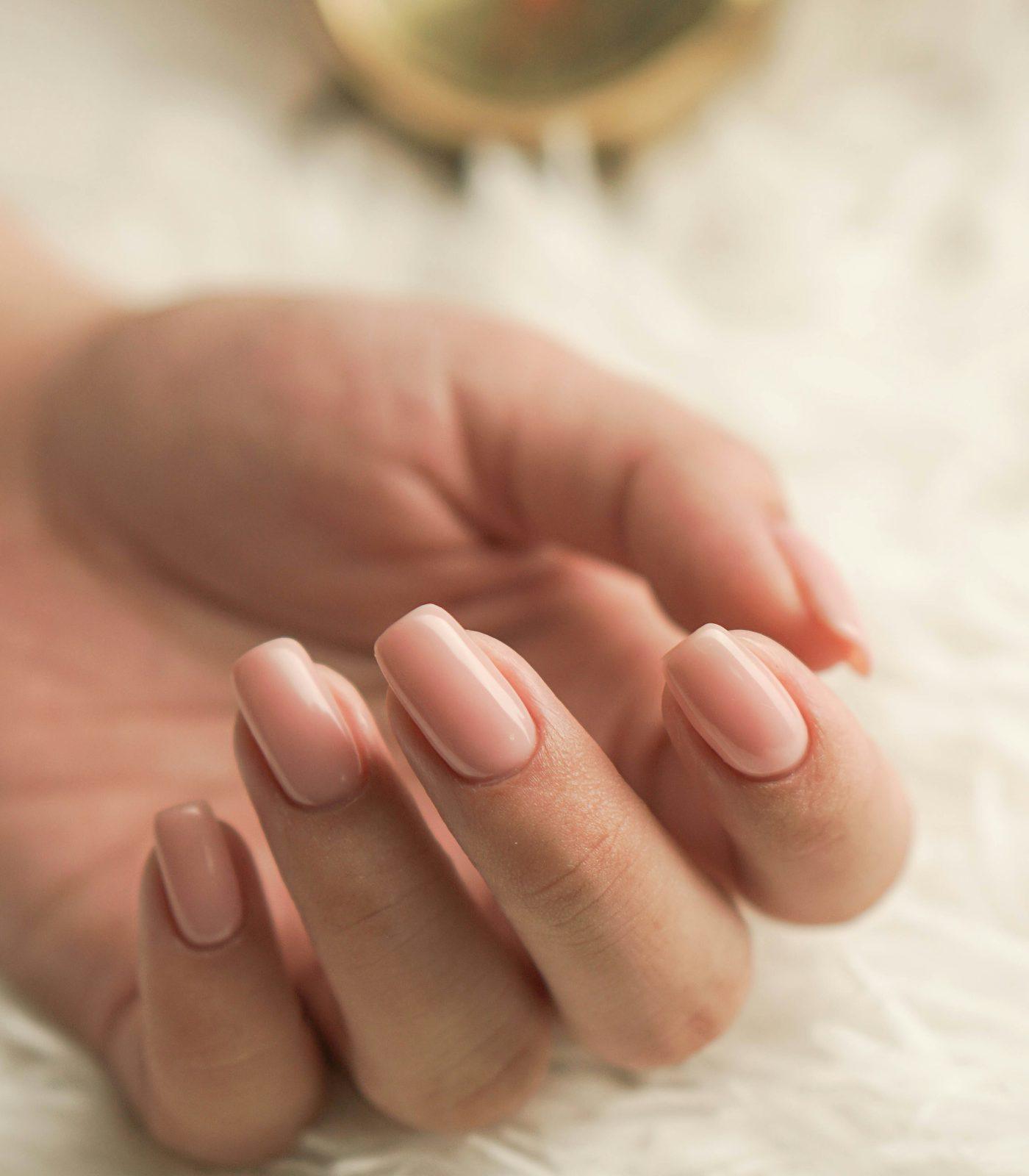 Soft nude manicure resting on white fur